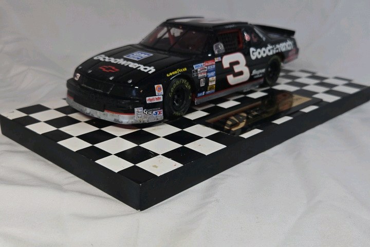 lot 115 image: Dale Earnhardt Sr. Goodwrench Monte Carlo  Black Diecast Number Seven Win Replica on Checkered Base
