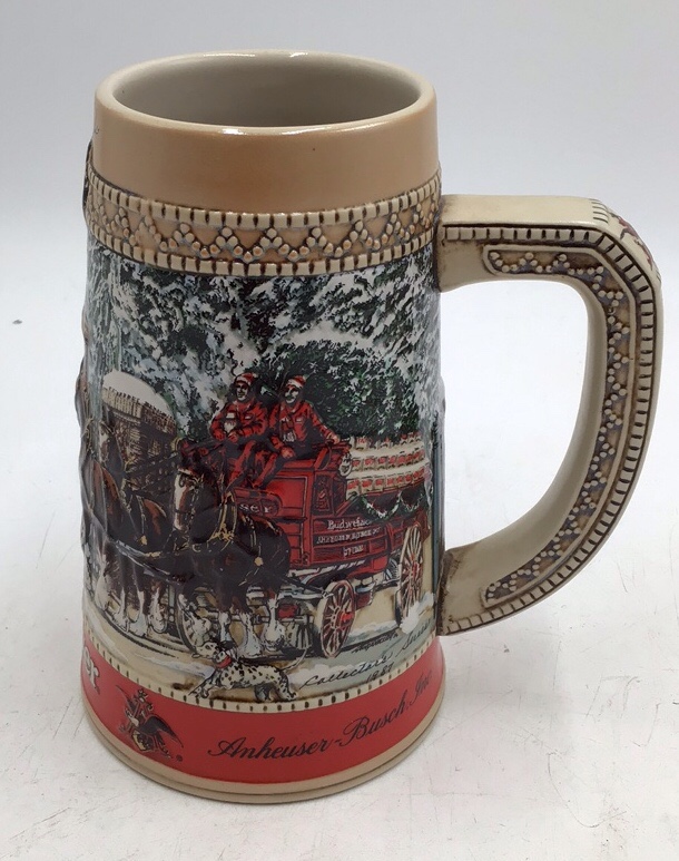 lot 155 image: Ceramic stein featuring Budweiser Clydesdales wagon parade scene at Grants Farm gates. Base marked handcrafted expressly for Anheuser-Busch C Series with winter parade description. Classic promotional beer stein design with sturdy ceramic form.