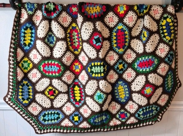 lot 231 image: Vintage Crocheted Granny Square Afghan  Multicolor Oval Floral Motifs on Brown Ground
