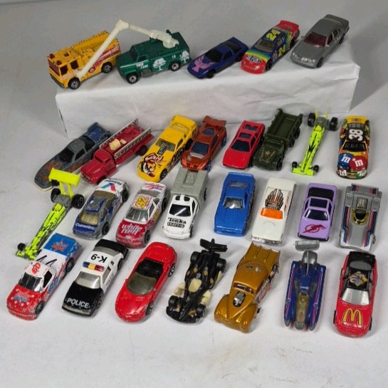 Mixed die cast cars including race cars, police vehicles, trucks, and dragsters. Various colors, styles, and themes with Hot Wheels and Matchbox type models.