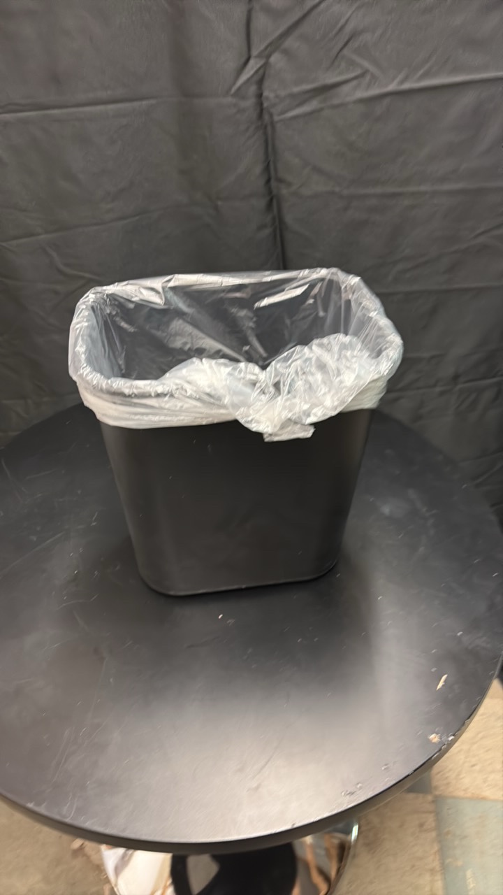Black Plastic Garbage Bin About One Foot in Height, Comes With Roll of Garbage Bags