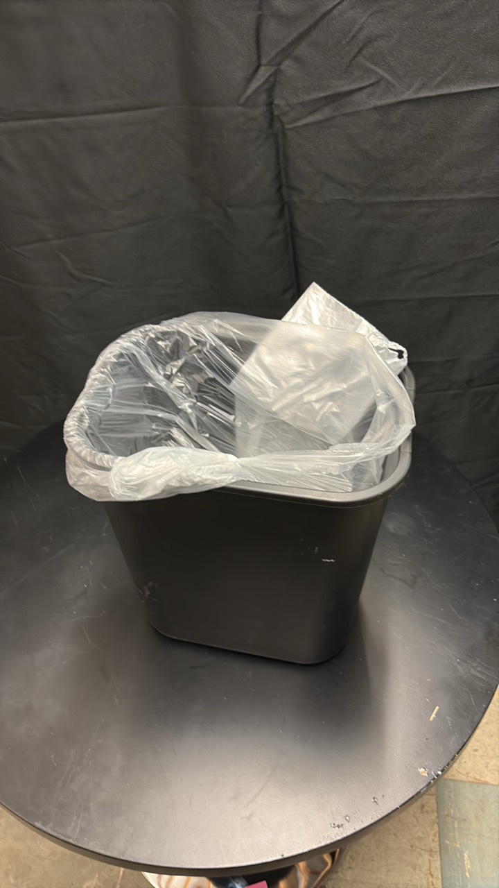 Black Plastic Garbage Bin About One Foot in Height, Comes With Roll of Garbage Bags