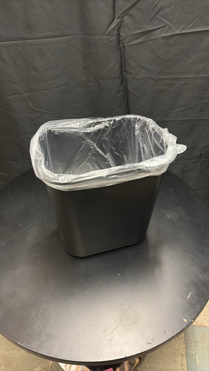 Black Plastic Garbage Bin About One Foot in Height, Comes With Roll of Garbage Bags